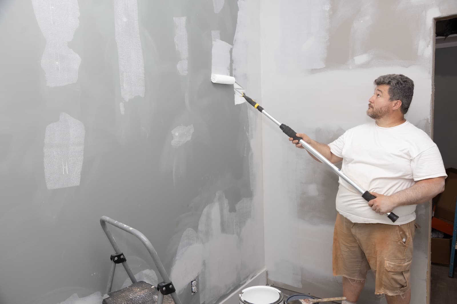 Painter applying interior wall paint with a roller in a residential room